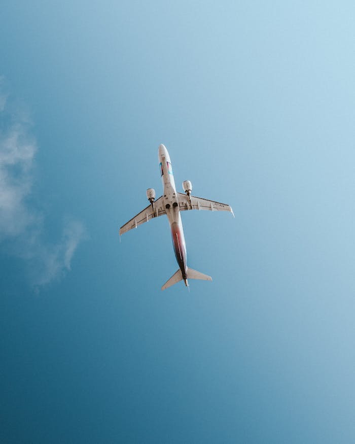 A commercial airplane captured from below against a clear blue sky in Tivat, Montenegro.