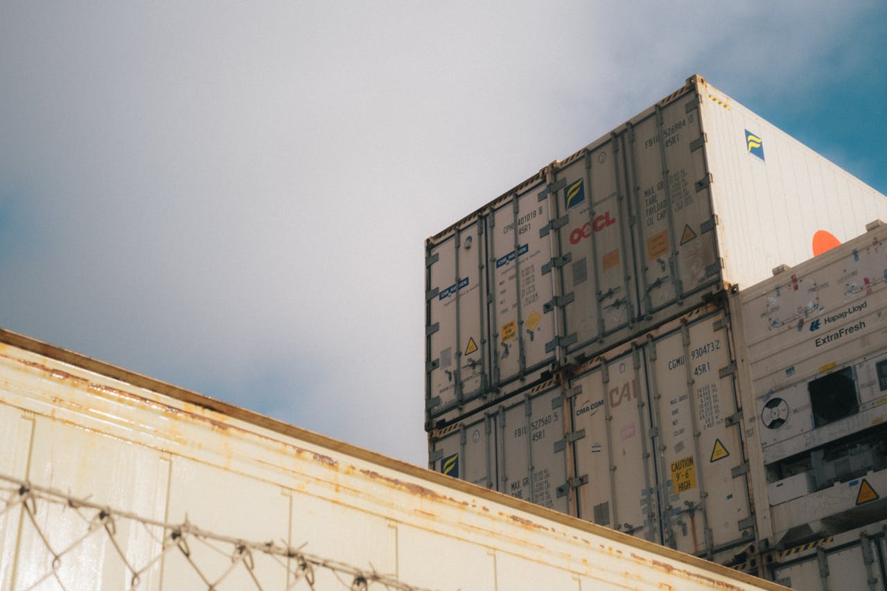 A low-angle view of stacked shipping containers against a cloudy sky, showcasing industrial logistics.